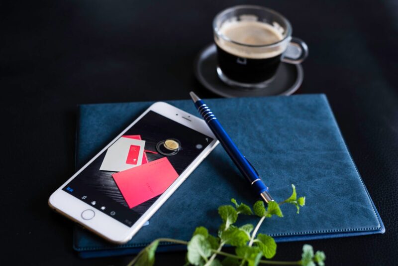 A stylish workspace featuring a coffee cup, smartphone, and notebook with pen.