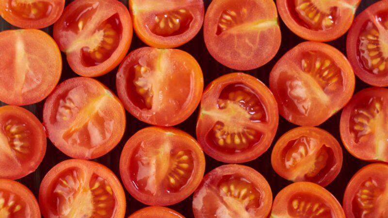 A vibrant flat lay of sliced cherry tomatoes showcasing their fresh, juicy interiors.