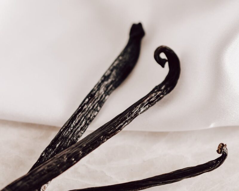 Detailed close-up of natural vanilla beans on a white background, perfect for culinary projects.